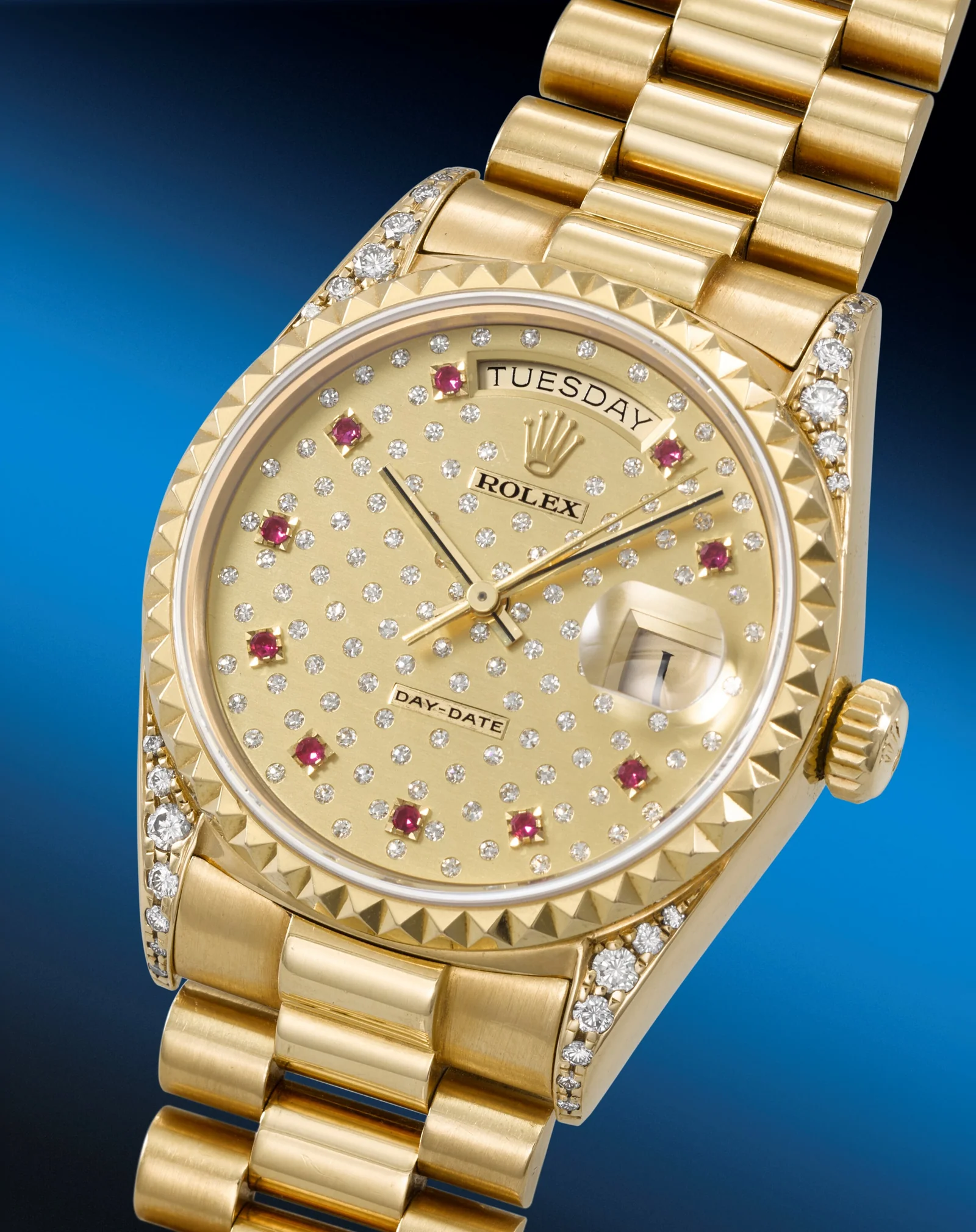Close view of the ruby and diamond Pleiades dial, pyramid bezel, and diamond-set lugs on a yellow-gold Day-Date 18018