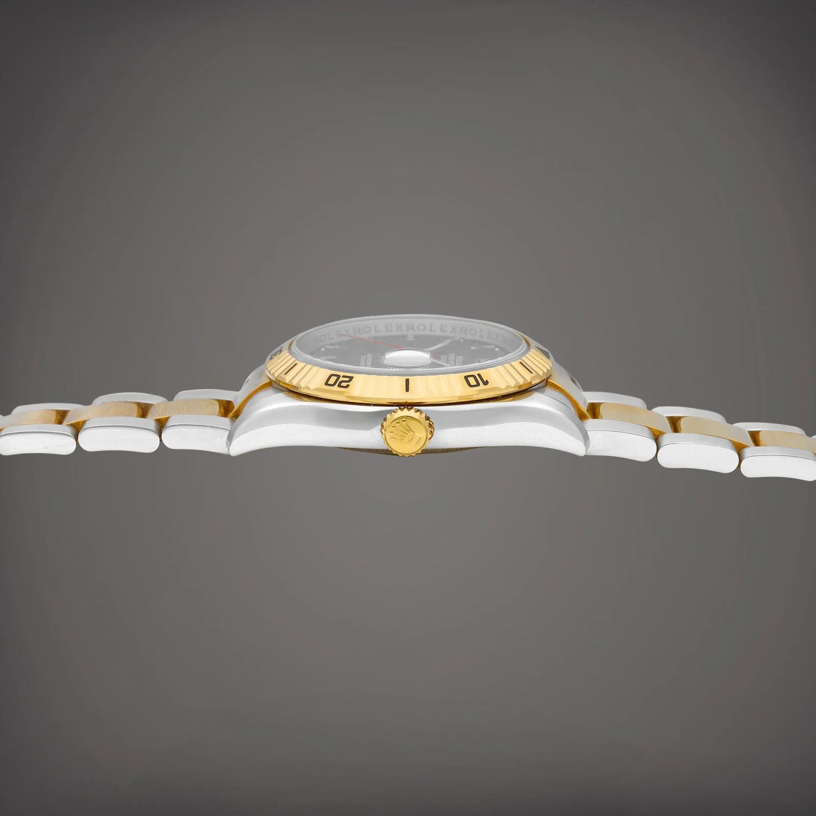 Side profile showing the yellow-gold rotating bezel, steel case and crown of a Rolex 116263
